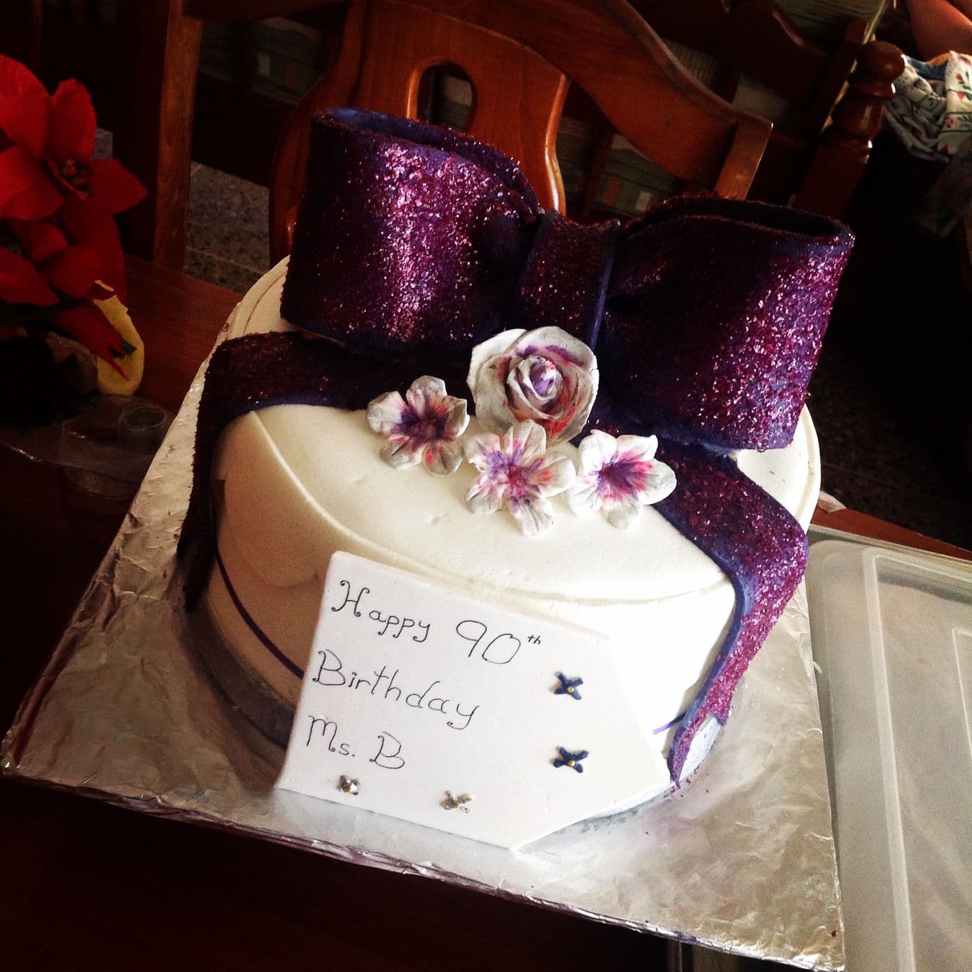 90th birthday cake with a purple glitter fondant bow, hand-made sugar roses and a hand-written plaque