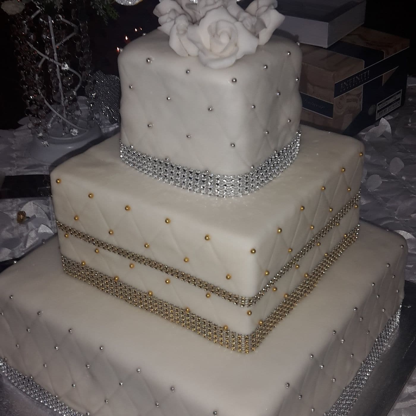 Close view of the same wedding cake showing quilted fondant, silver and gold crystal bands and dragée detailing on each tier
