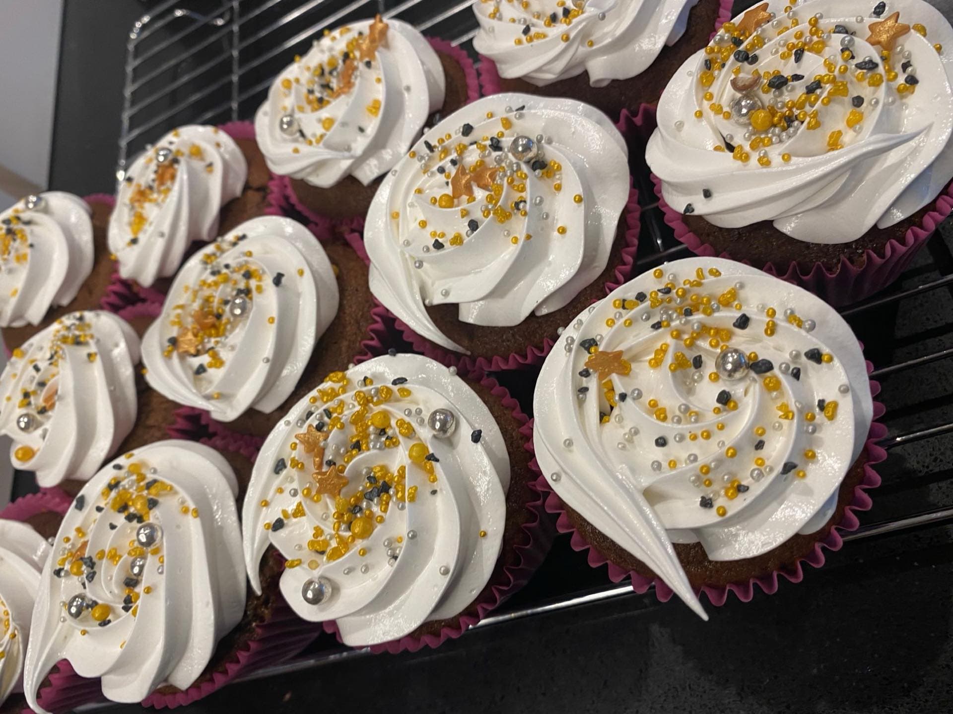 A batch of hand-piped cupcakes cooling on the rack