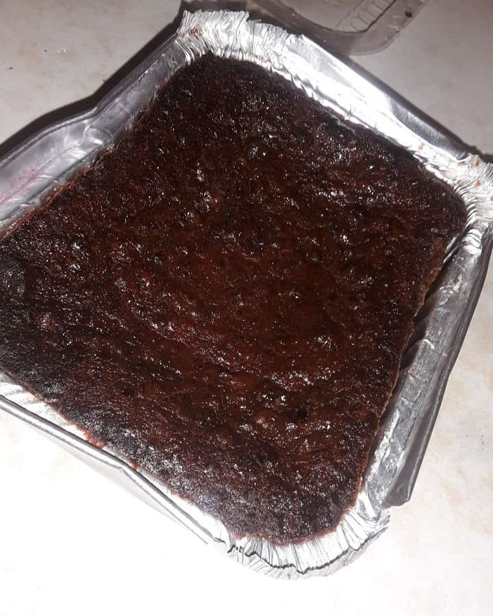 A dark, un-iced rum fruit cake in a foil baking tray