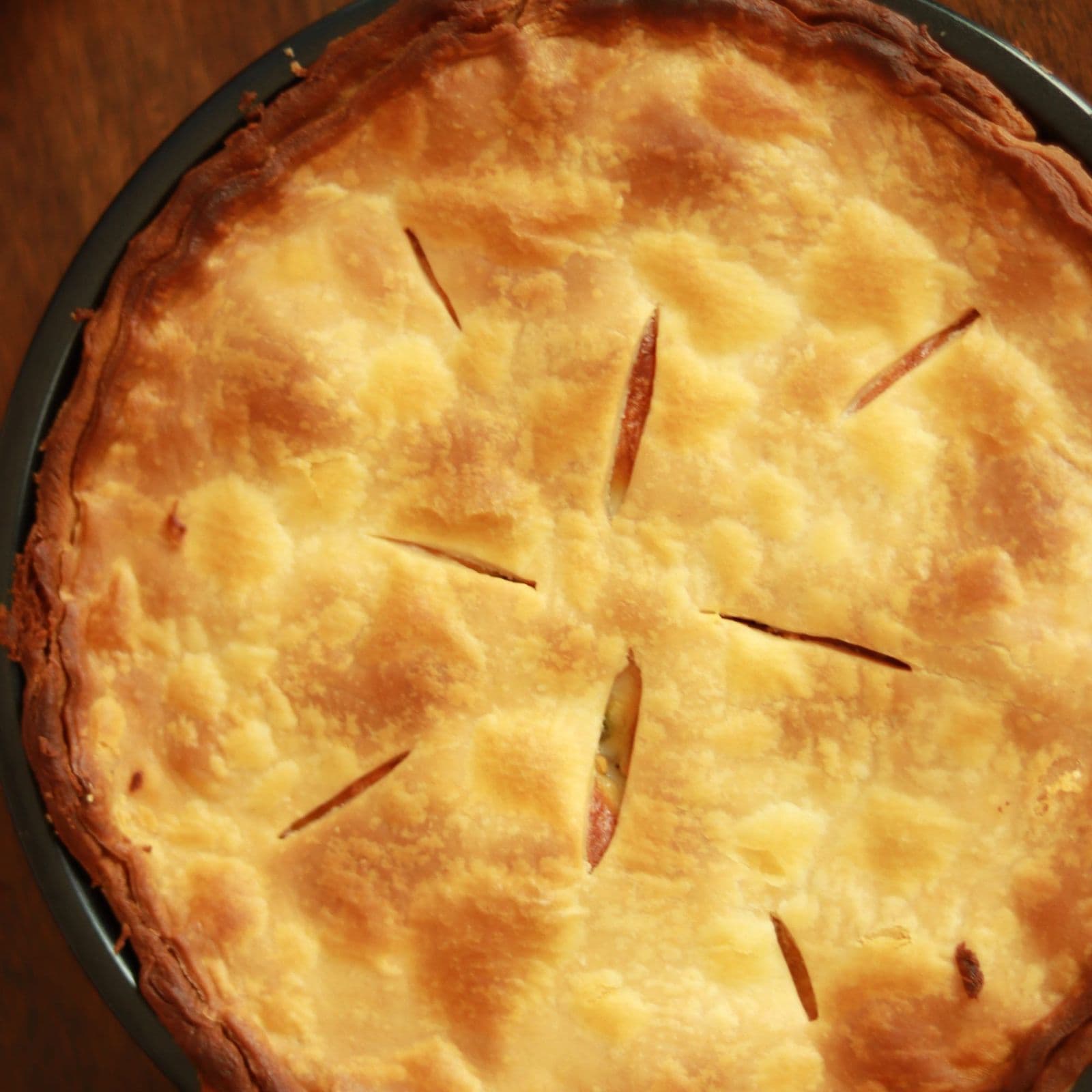 A double-crust pie seen from above, steam vents cut through the golden lid