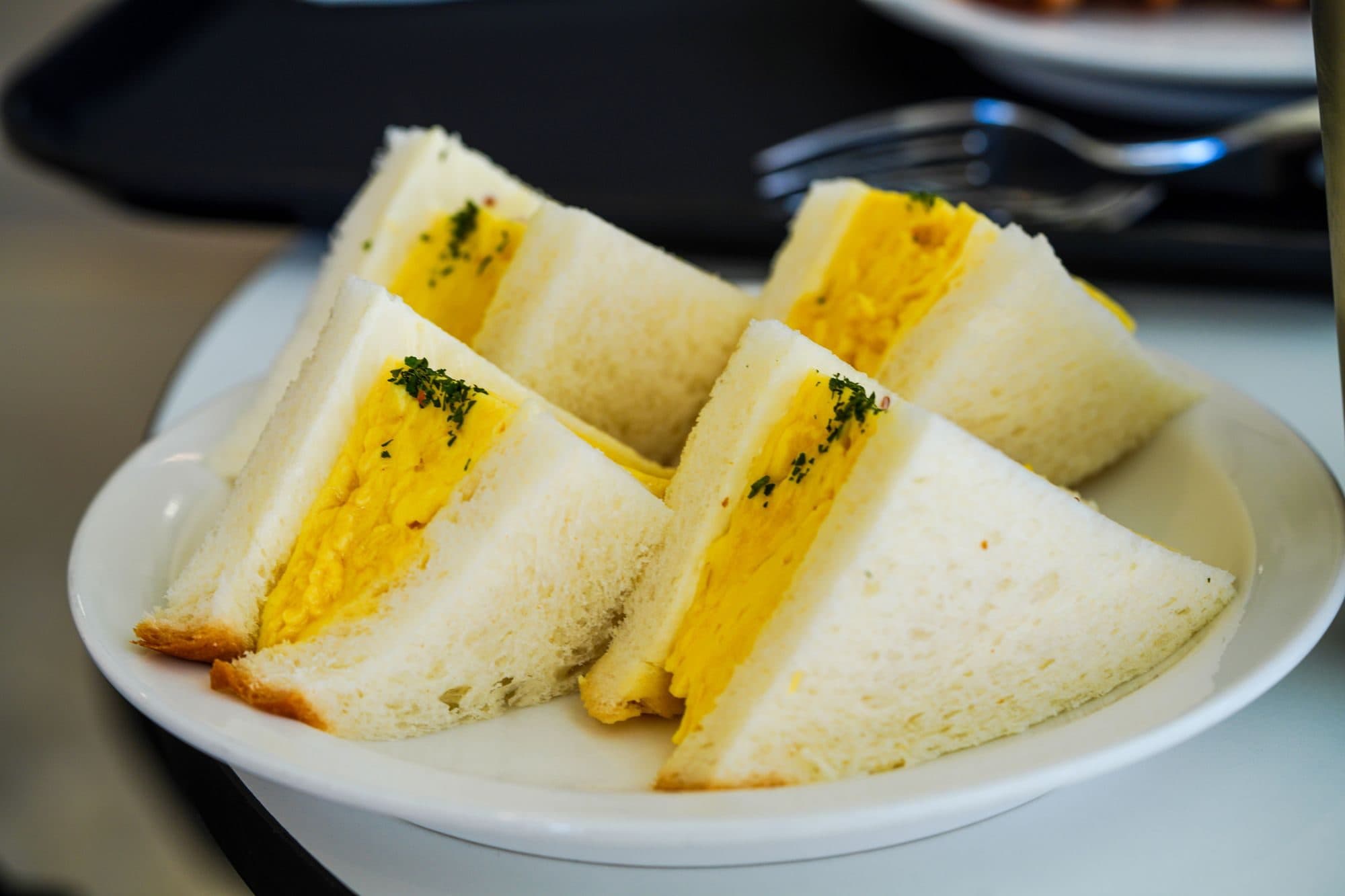 Egg mayonnaise sandwiches cut into triangles on a white plate