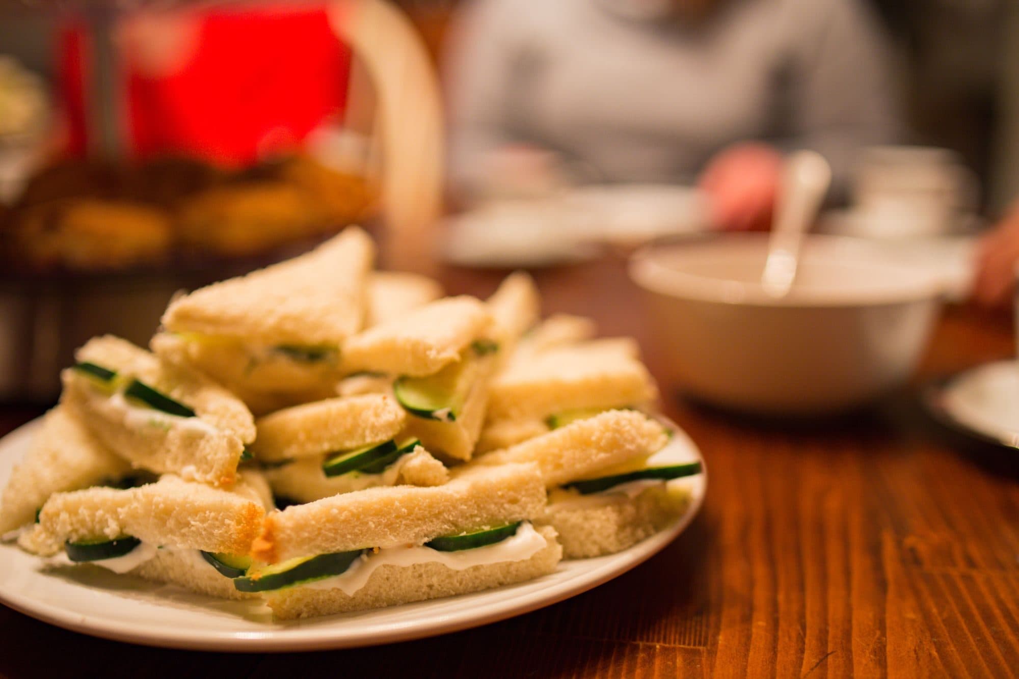 Cucumber finger sandwiches piled on a plate