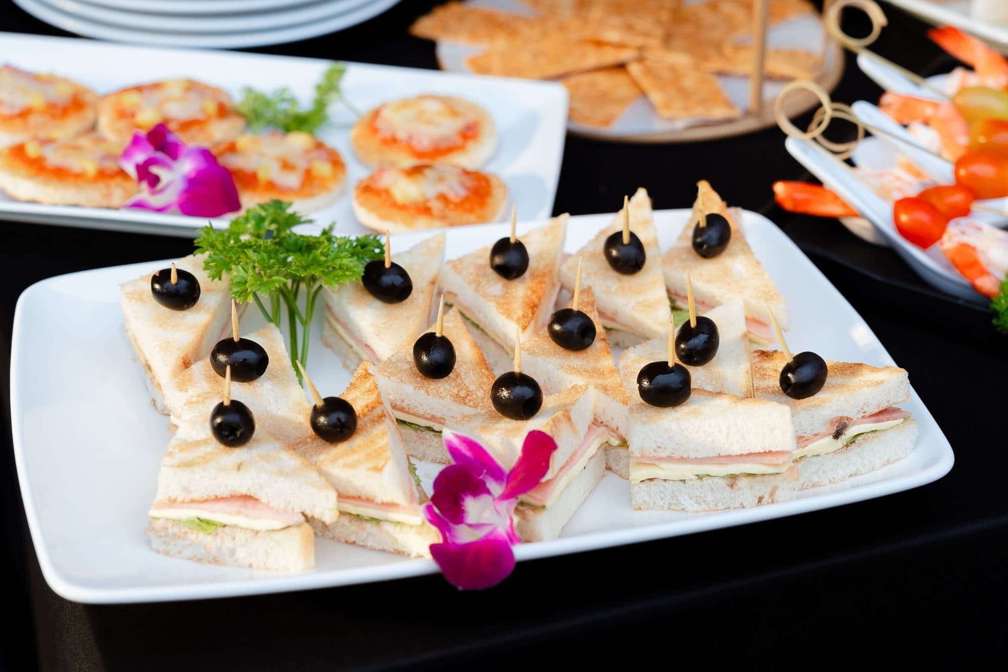 Mini triangle sandwiches with black olives on a buffet platter