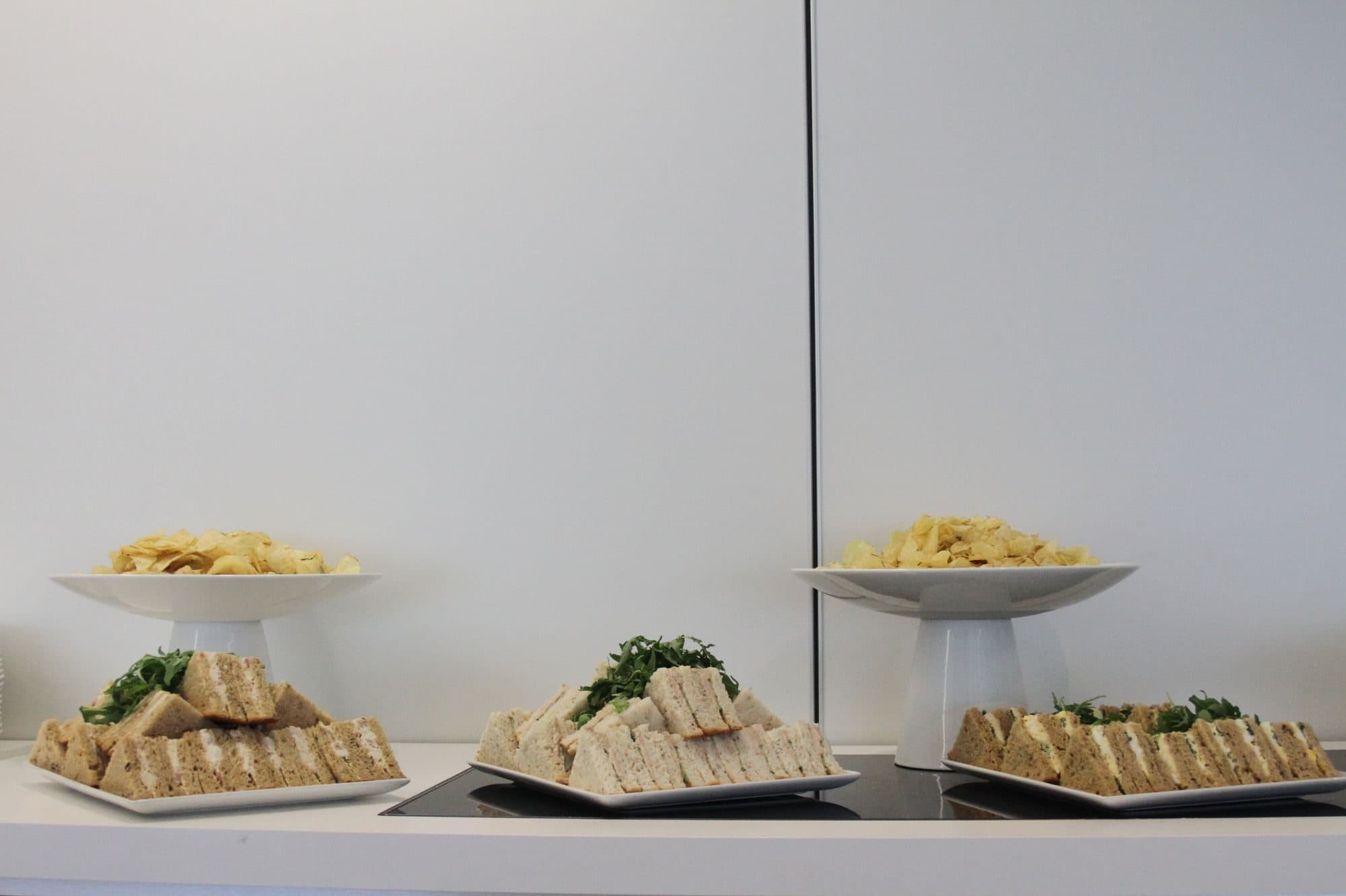 Trays of quartered sandwiches and crisps set out for a meeting