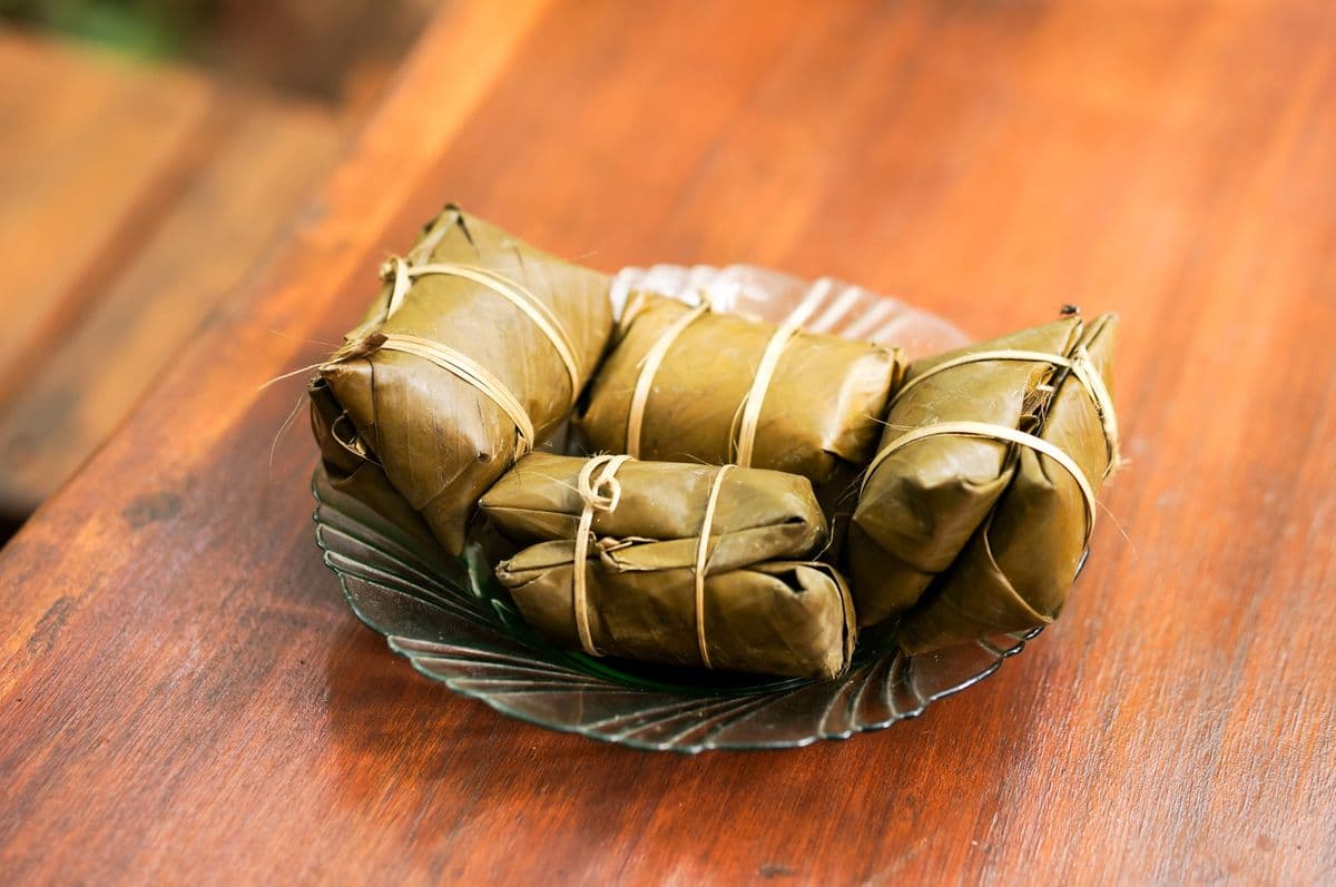Banana-leaf-wrapped parcels on a glass plate on a wooden table