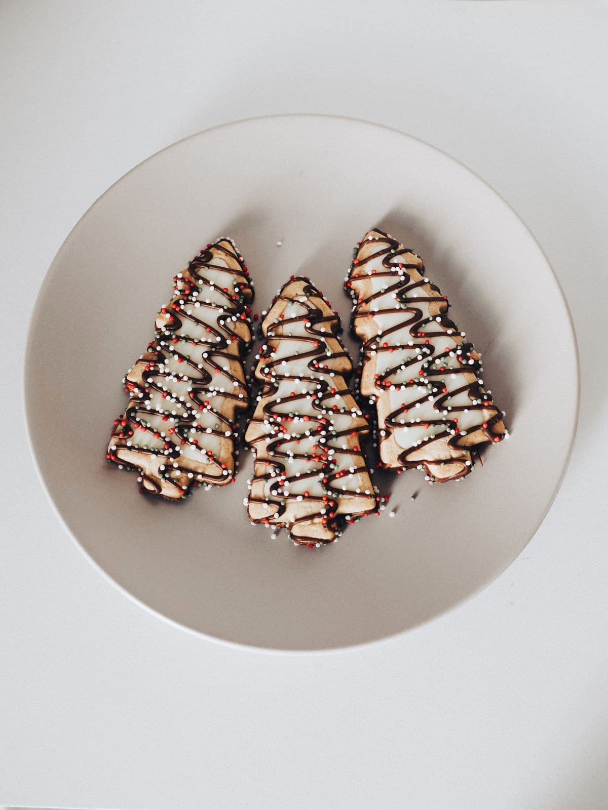 Tree-shaped holiday cookies with icing and sprinkles on a plate